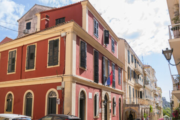 Naklejka premium A historic, terracotta-colored building with a Serbian flag flying from a window in the narrow streets of the old town of Corfu, Greece, showcasing a unique cultural connection.