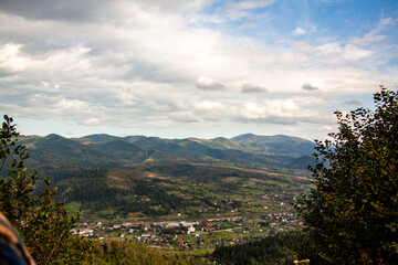Obraz premium church, city between mountains, clouds float over peaks, distant plan, houses, in valley, landscape, Panorama, skyline, summer, sunny, tourism, travel, trees