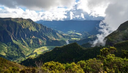 Fototapeta premium Lush green valley between steep mountain ranges, with cloud cover partially obscuring the peaks