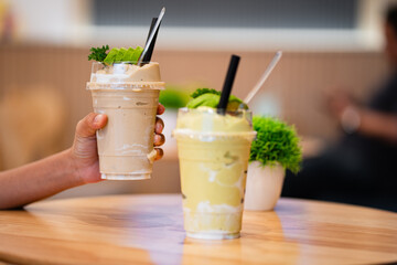 Hand holding glass of fresh fruit juice blended Yogurt fresh fruit smoothie avocado, taro with milk.
