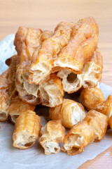 Golden-brown Chinese fried dough sticks stacked on parchment paper, showing crispy texture and airy interior, a popular Asian breakfast street food snack.
