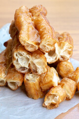 Golden-brown Chinese fried dough sticks stacked on parchment paper, showing crispy texture and airy interior, a popular Asian breakfast street food snack.