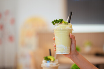 Hand holding glass of fresh fruit juice blended Yogurt fresh fruit smoothie avocado with milk.	