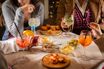 At a lively bar table, unseen guests enjoy food and drinks—cocktail and small bites fill the scene with flavor, conviviality, and Italian aperitivo vibes.