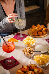 At a lively bar table, unseen guest enjoy food and drinks—cocktail and small bites fill the scene with flavor, conviviality, and Italian aperitivo vibes.