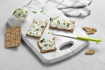 Crispbread toast with Cottage Cheese and parsley on white wooden board.