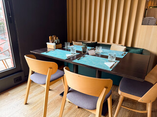 Restaurant corner table with wooden chairs and placemats ready for dining. Hospitality, comfort, and atmosphere created for social gathering and guest leisure.