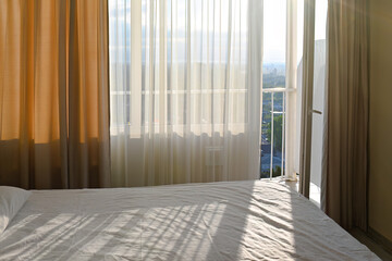 Rays of sun penetrate the room through the window and fall on the bed. Morning in a sunlit bedroom.