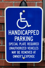 Handicapped Parking Sign Against Brick Wall Requiring Special Plate