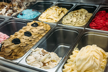Bright assortment of gelato in multiple flavors including licorice, pistachio, vanilla, and berry...
