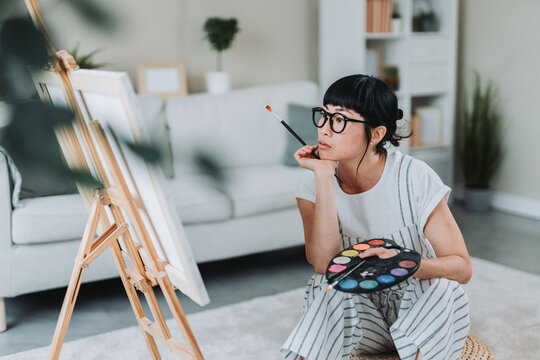 Female japanese artist painting on canvas at home studio