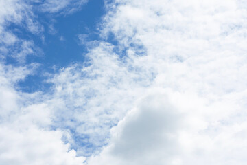Bright and peaceful view of a blue sky filled with scattered, fluffy white clouds. Concept for backgrounds, relaxation, freedom and nature.