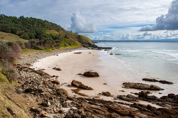 Secluded sandy beach with rocks and green hills in the Byron Bay area, New South Wales, Australia