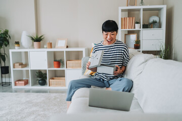 Excited mature japanese woman opening a gift box during a video call