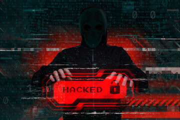 Masked hacker behind a computer with a red warning Hacked. Concept of cybersecurity threat, attacks on data and online systems.
