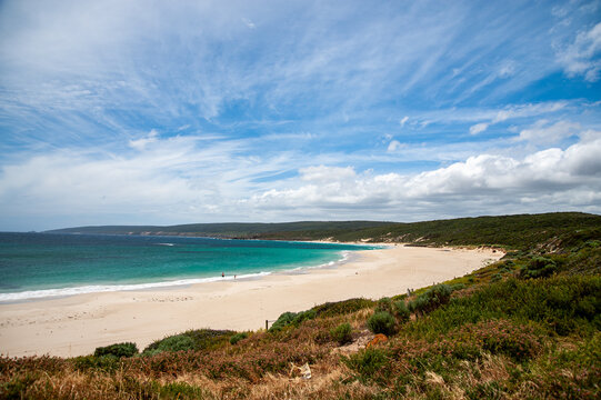 Crystal clear wave breaking on the sandy beach of Yallingup, Western Australia, with cliffs in the background
