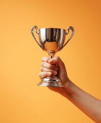 Hand raised with a trophy cup on a plain backdrop, studio photo