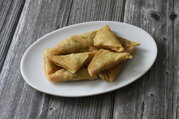Ten pieces samosas on white plate.
