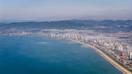 Distant aerial view of Balne&aacute;rio Pi&ccedil;arras with low clouds over coastline.