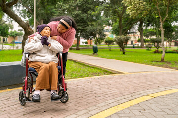 Fototapeta premium Nurse assisting elderly woman in wheelchair in park