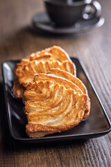 Le sfoglie. Crispy sweet pastry on plate on wooden table.
