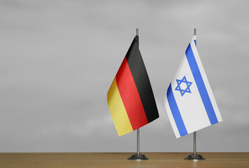 Tabletop flags of Germany and Israel on stands on a gray blurred background
