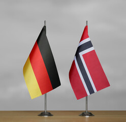 Tabletop flags of Germany and Norway on stands on a gray blurred background