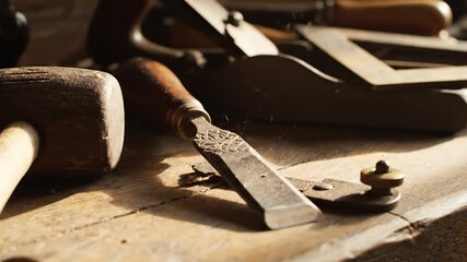 Close-up on an assortment of antique woodworking tools, including a mallet, chisel, and plane, resting on a weathered wooden surface - Powered by Adobe