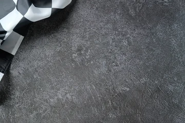 Fototapete Rund Formel 1 Checkered racing flag draped over textured asphalt surface  © photoguns