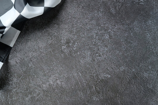 Checkered racing flag draped over textured asphalt surface