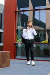Red-haired man professional speaking on mobile while walking