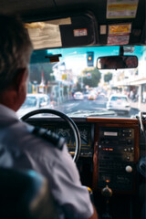 Taxi driver sitting behind the wheel of a yellow cab, visible through the side window, urban street in the background. Transportation, city life, and professional drivers.