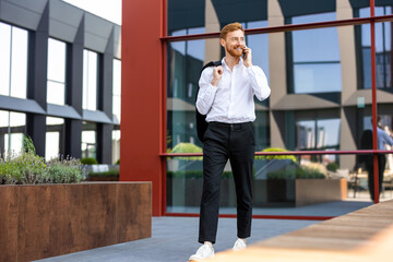 Confident man in formal wear walking in urban area speaking on mobile phone