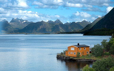Fototapeta premium Orange house overlooking picturesque norwegian fjord and mountains