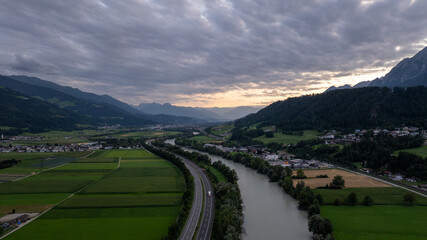 Aerial view of the river inn valley with highway a12, agricultural fields, villages, and mountains during a dramatic sunset in Tyrol, Austria