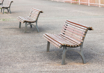 Rows of wooden benches with metal frames located on a paved area