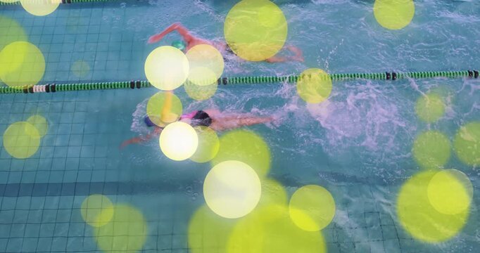 Entering green-capped man and blue-capped woman front crawl racing for fitness yellow bokeh overlay