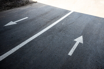 Opposite directional arrows painted on asphalt with dividing line, concept of choice, conflict, opposite paths and decision making.