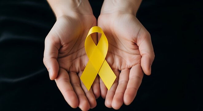 Hands holding yellow ribbon symbol for childhood cancer awareness and support - Powered by Adobe