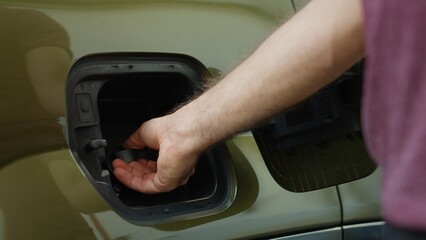 Extreme close up of driver closing electric car charging port flap after recharging depleted...