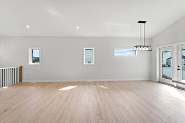 Large open living room with a white wall and wooden floors