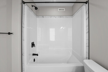 White bathtub with a black faucet and a black towel rack
