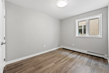 Very empty room with a white wall and wooden floor