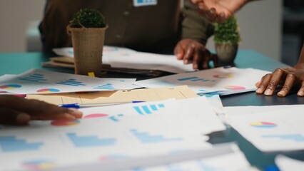 Business colleagues attending in a late night briefing session for teamwork, exchanging documents and reviewing finance updates. Aligning objectives through problem solving. Camera B.