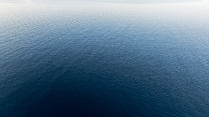 Obraz premium Deep blue water surface gently rippling under a soft light, creating a mesmerizing gradient from dark to light, in Kassandra, Greece