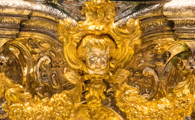 Cherub angel in overloaded Rococo golden relief in Mosque-Cathedral of Cordoba. Rich Baroque...