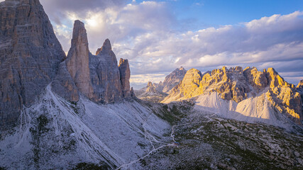 Stunning view of the iconic Tre Cime di Lavaredo peaks glowing in golden evening light above rocky alpine valleys in the Dolomites Italy