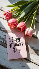 Pink tulips and Happy Mothers Day card on a weathered white wooden surface