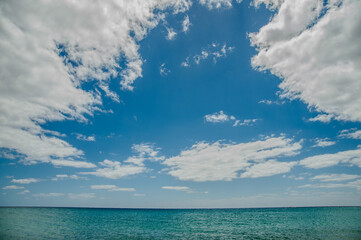 Minimalist seascape with turquoise ocean and cloudy blue sky, symbolizing peace and tranquility