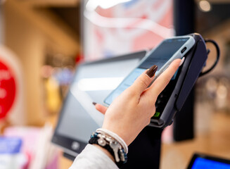 Woman's Hands With Smartphone At Self-Checkout Paying For Purchases Close-Up
